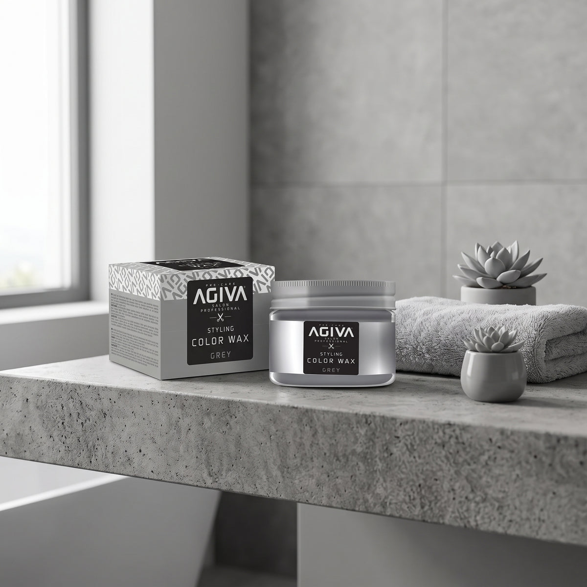 AGIVA Styling Color Wax Grey i sølvglas ved siden af æske på betonbord med håndklæde og succulenter.