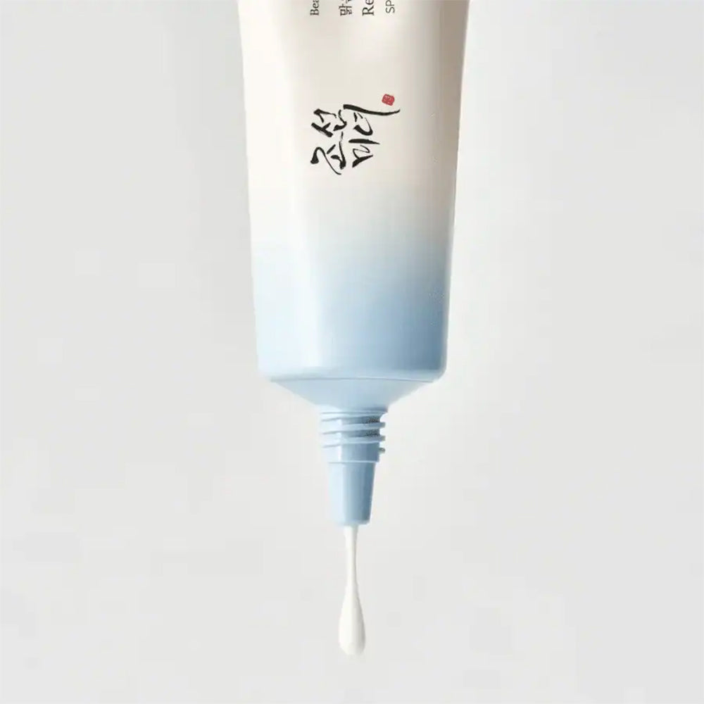 Dråbe af Beauty of Joseon Relief Sun Aqua-Fresh : Rice + B5 SPF50+ PA++++ 50ml presses ud af lyseblå tube.