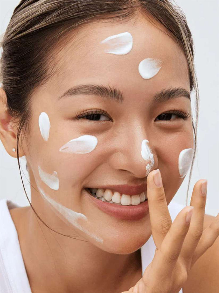 Smilende kvinde med solcreme i ansigtet påfører Beauty of Joseon Relief Sun Aqua-Fresh: Rice + B5 SPF50+ PA++++ 50ml.