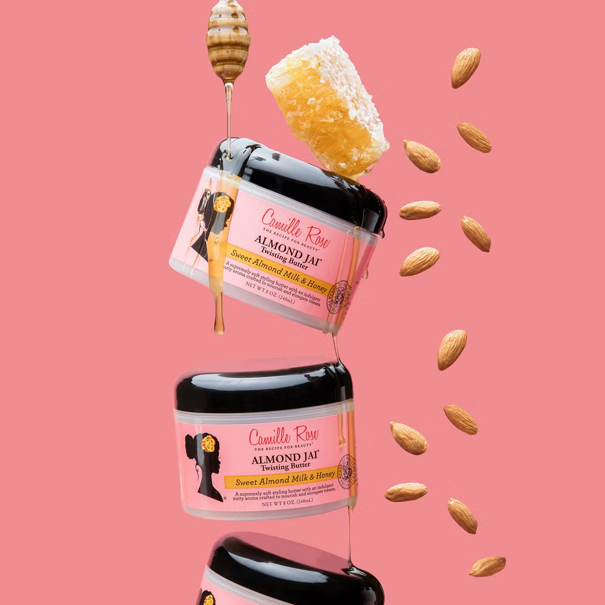Flere Camille Rose Almond Jai Twisting Butter på lyserød baggrund med flydende honning og mandler.
