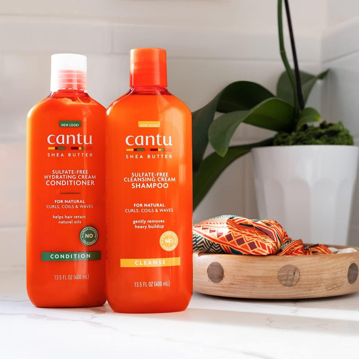 To orange flasker: Cantu Shea Butter Hydrating Cream Conditioner og Cleansing Cream Shampoo.